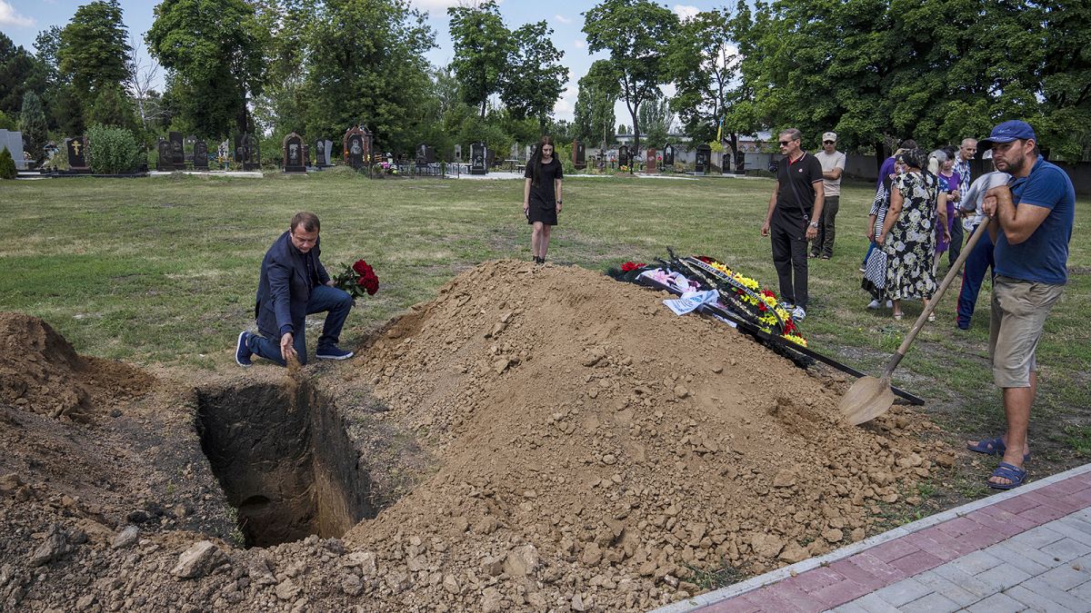 Pokrovsk mayor Ruslan Trebushkin, throws dirt on the coffin of 40-year-old Volodymyr Miroshnychenko who was killed on the frontlines of Marinka, 15 July 2022