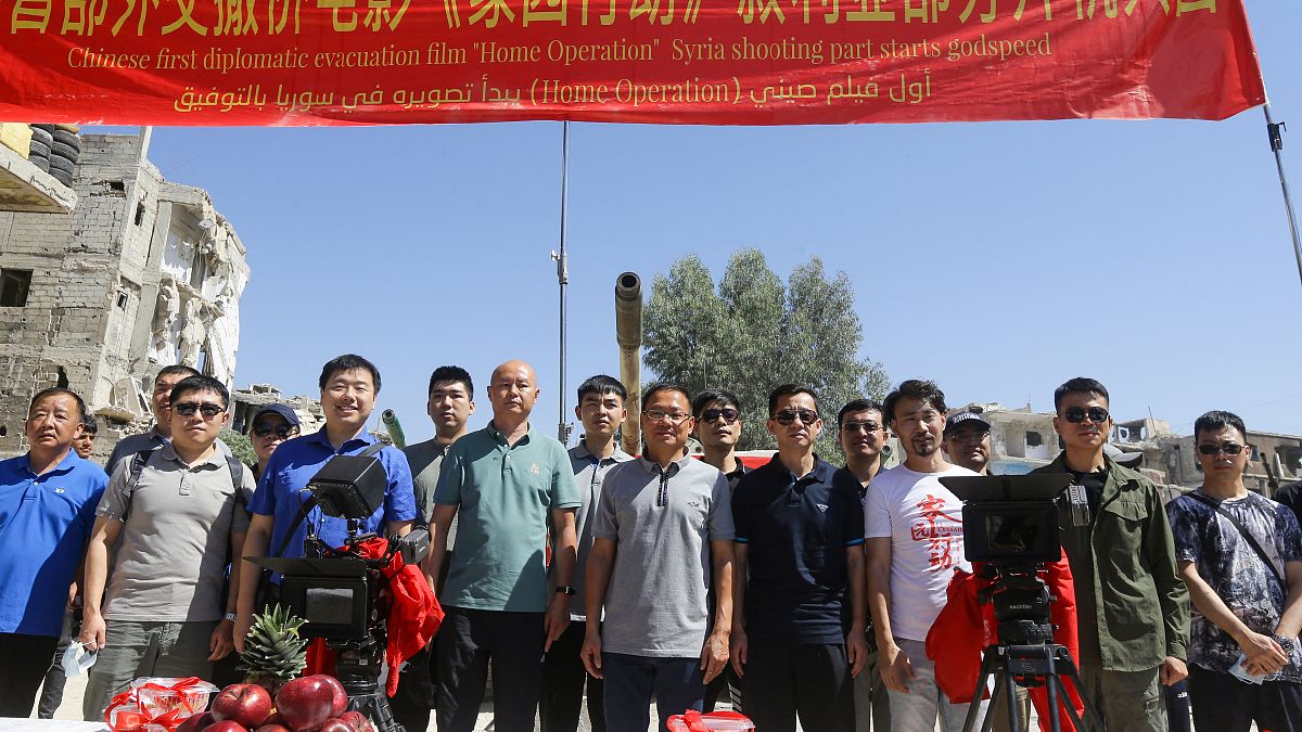 السفير الصيني لدى سوريا فنغ بياو (وسط) يقف لالتقاط صورة مع الممثلين وطاقم عمل الفيلم في حي الحجر الأسود بالعاصمة السورية دمشق في 14 يوليو 2022 .