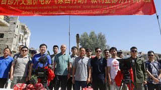 السفير الصيني لدى سوريا فنغ بياو (وسط) يقف لالتقاط صورة مع الممثلين وطاقم عمل الفيلم في حي الحجر الأسود بالعاصمة السورية دمشق في 14 يوليو 2022 .