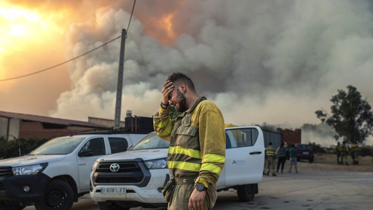Пожарный плачет рядом с очагом лесного пожара в районе Лосасио на северо-западе Испании в воскресенье 17 июля 2022 г.