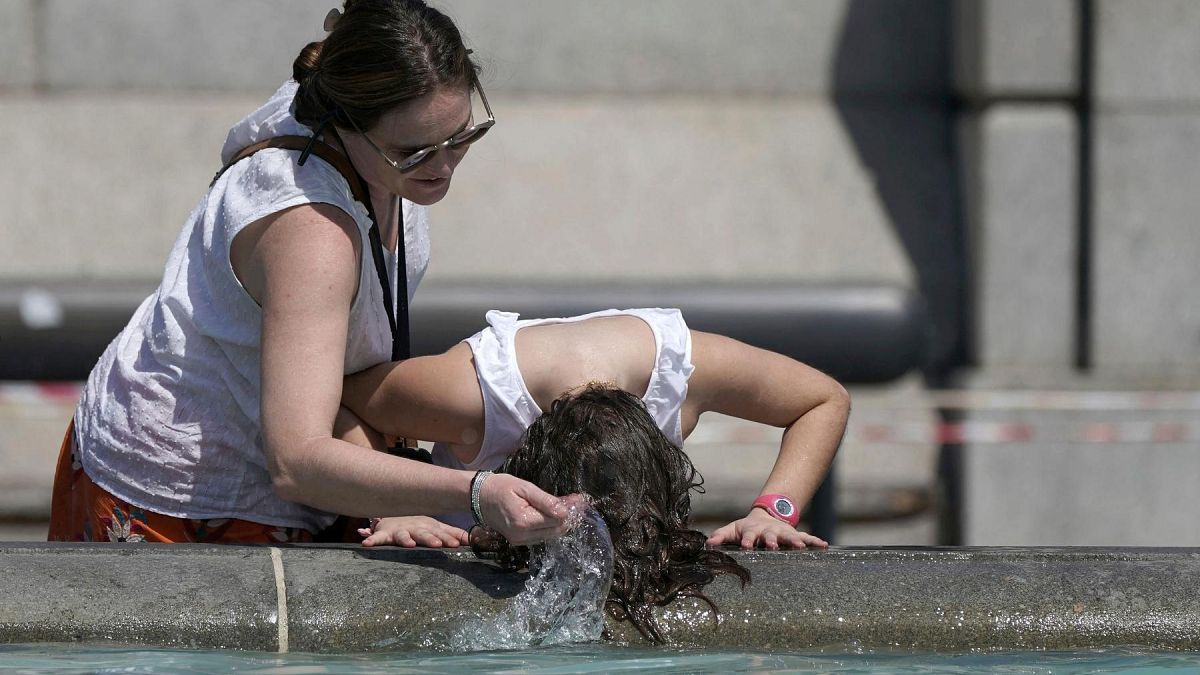 A person wets their hair in a fountain at Trafalgar Square in central London, Tuesday July 19, 2022.