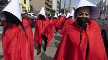 Manifestantes encenaram uma uma cena baseada no livro distópico "Os Contos da Serva" usando vestidos vermelhos e lenços brancos