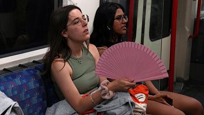 A woman holds a fan as she travels on the London Underground during a heatwave in London, Britain, July 17, 2022.