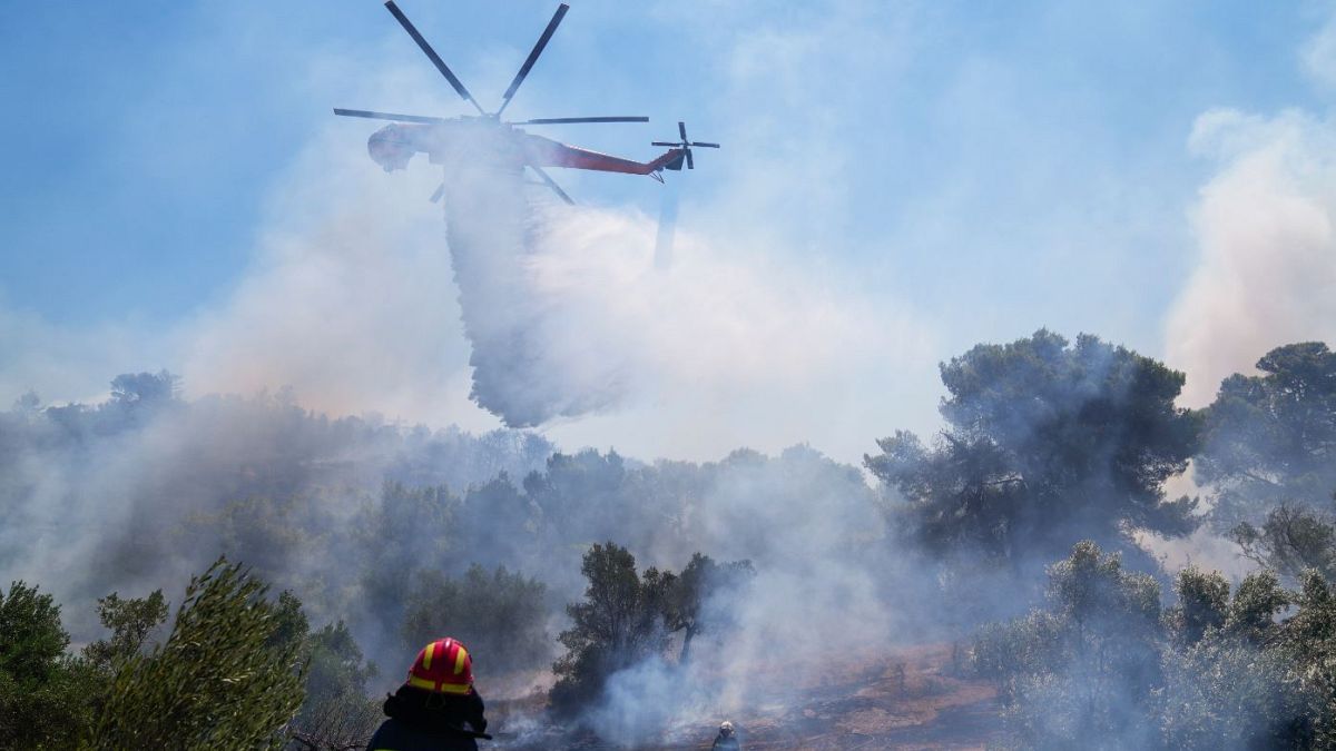 A firefighting helicopter dumps water in the area of Panorama Palinis, east of Athens.