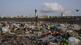 Egy férfi sétál a műanyaggal és más szeméttel borított Arab-tenger partján Mumbai-ban, 2022. június 5-én