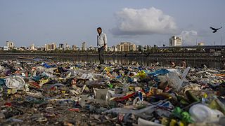Egy férfi sétál a műanyaggal és más szeméttel borított Arab-tenger partján Mumbai-ban, 2022. június 5-én