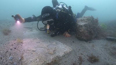 Diver with a decorated Purbeck stone gravestone on the 13th century Mortar Wreck, Poole Bay, Dorset.