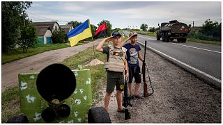  ماكسيم وأندري يلقيان التحية على الجنود الأوكرانيين عند نقطة  تفتيش على الطريق السريع في خاركيف، أوكرانيا، 20 يوليو، 2022.