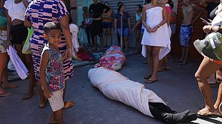 A favela lakói körbecsavart testet állnak körbe a razzia után