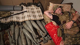 Ukrainian serviceman "Piter" rests on his bed near mortar shells at the frontline in Kharkiv region, Ukraine, Friday, July 22, 2022.