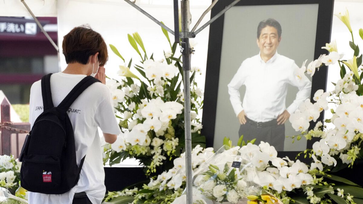 شخص يقدم الزهور والصلاة لرئيس الوزراء السابق شينزو آبي، في معبد زوجوجي قبل جنازته في طوكيو، اليابان، الإثنين 11 يوليو 2022