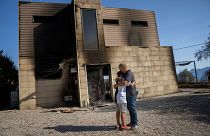 Alex Codonyer abraza a su hijo Alan junto a su casa quemada durante un incendio forestal cerca de la localidad de El Pont de Vilomara, España, el 19 de julio de 2022.