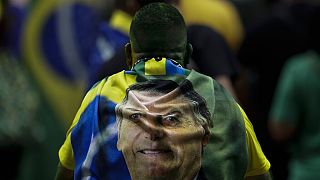 Jair Bolsonaro egyik támogatója a brazil elnököt ábrázoló törülközővel a hátán.
