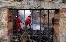 Firefighters douse smouldering rubbles in a burnt house.