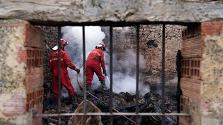 Firefighters douse smouldering rubbles in a burnt house.