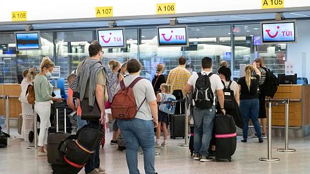Passengers hand in their luggage at TUI check-in counters at the airport in Hanover, Germany.