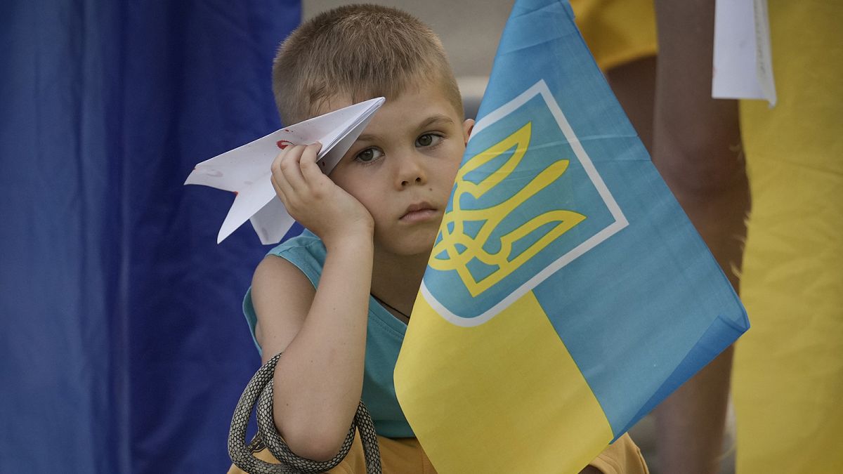 A boy holds a paper plane during a protest by Ukrainian refugees in Bucharest, 23 July 2022