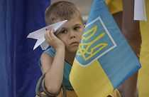 A boy holds a paper plane during a protest by Ukrainian refugees in Bucharest, 23 July 2022