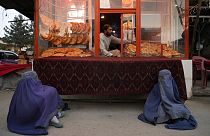 Deux mendiantes attendent de recevoir l'aumône devant une boulangerie à Kaboul, en Afghanistan, dimanche 15 mai 2022.