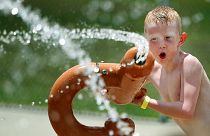 Criança brinca com com expersor de água na via pública