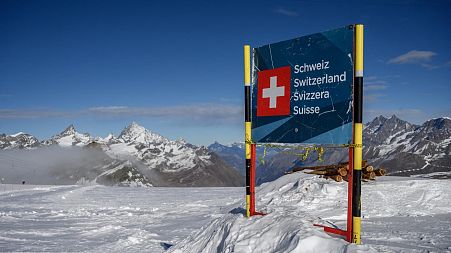 A banner marking the Swiss border near the 3,480-metre high Rifugio Guide del Cervino refuge at Testa Grigia peak.