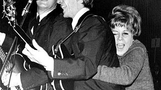 A young Swedish fan hugs George Harrison as The Beatles play at a pop festival in Stockholm, Sweden, Oct. 26, 1963.