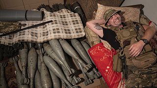 Ukrainian serviceman "Piter" rests on his bed near mortar shells at the frontline in Kharkiv region