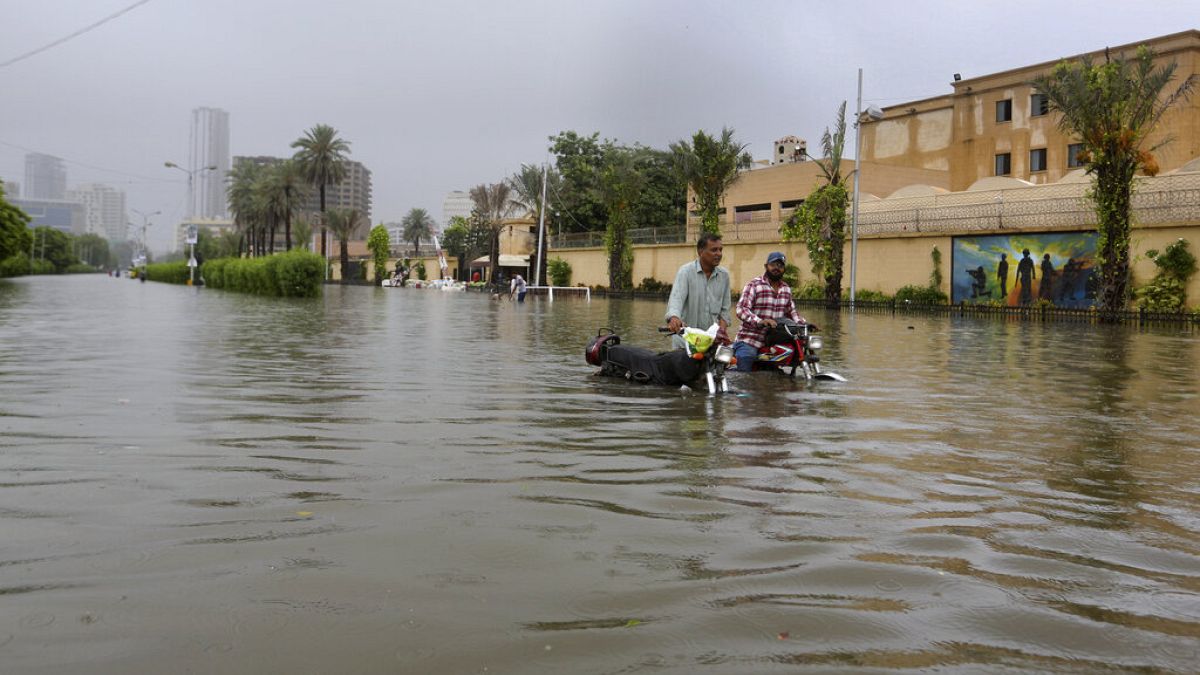 Motorbiciklisek az elöntött Karacsi egyik utcáján, július 25-én. Júnus közepe óta több mint 300-an haltak meg az áradásokban