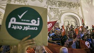 تونسي يحمل لافتة كتب عليها "نعم للدستور الجديد" احتفالا باستطلاعات الرأي التي تشير إلى التصويت لصالح الدستور الجديد، في تونس العاصمة، الإثنين 25 يوليو / تموز 2022