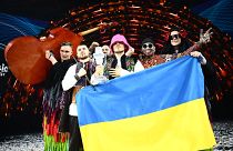 Kalush Orchestra pose onstage with the winner's trophy and Ukrainian flags after winning the Eurovision Song Contest 2022