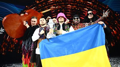 Kalush Orchestra pose onstage with the winner's trophy and Ukrainian flags after winning the Eurovision Song Contest 2022