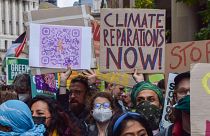 A protester holds a 'Climate Reparations Now' placard during the demonstration in the City of London.