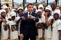 Macron poses with young women in traditional costumes as they celebrate the Abomey Treasures, during his visit to the French College in Benin, 27 July 2022.