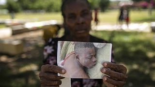 A woman holds up a photo of her son, who was killed in clashes between armed gangs in Cite Soleil, in Port-au-Prince, Haiti