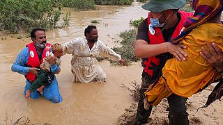 Des secouristes aident des habitants à évacuer d'une zone inondée par de fortes pluies, à Lasbella, un district de la province du Baloutchistan, dans le sud-ouest du Pakistan.
