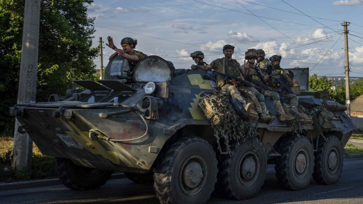 Ukrainian soldiers ride a tank on road to Kherson