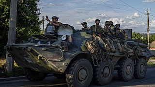 Ukrainian soldiers ride a tank on road to Kherson