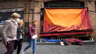 Pedestrians pass homeless people sleeping in front of a closed retail unit in London, 13 April 2022 (AP Photo/Kirsty Wigglesworth)