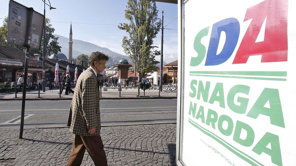 A Bosnian man passes by an election poster of the Party of Democratic Action (SDA) in Sarajevo, Bosnia, Saturday, Oct. 6, 2018.