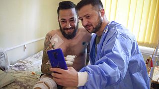 Ukrainian President Volodymyr Zelenskyy, right, takes selfie with a wounded soldier injured fighting Russian troops, 29 July.