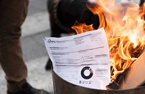 A utility bill burns during a protest by shopkeepers against the costs of living, in Turin, Italy, Tuesday, Oct. 11, 2022. 