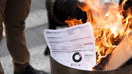 A utility bill burns during a protest by shopkeepers against the costs of living, in Turin, Italy, Tuesday, Oct. 11, 2022.