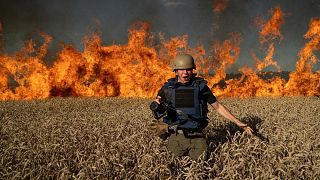 Photojournalist Evgeniy Maloletka runs from the fire in a burning wheat field during his assignment after Russian shelling, a few kilometres from Ukrainian-Russian border in t