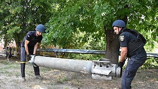Спасатели несут обломок ракеты на спортивной площадке после удара в Николаеве, 31 июля 2022 года.