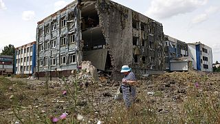Женщина проходит мимо частично разрушенной в результате ракетного обстрела школы в Константиновке Донецкой области, 25 июля 2022 года.