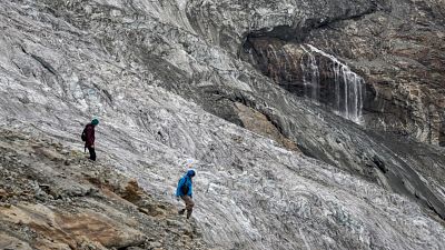 Hikers are seen walking next to the melting Fee Glacier above the Swiss alpine resort of Saas-Fee. Hikers are seen walking next to the melting Fee Glacier above the Swiss alpine resort of Saas-Fee.