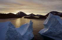 Nagy jéghegyek lebegnek a vizen napfelkeltekor a grönlandi Kulusuk közelében.