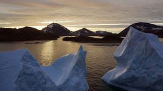 Nagy jéghegyek lebegnek a vizen napfelkeltekor a grönlandi Kulusuk közelében. 