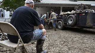 Un hombre se toma un descanso mientras los voluntarios limpian la propiedad dañada por las inundaciones de una casa Kentucky, el sábado 30 de julio de 2022.