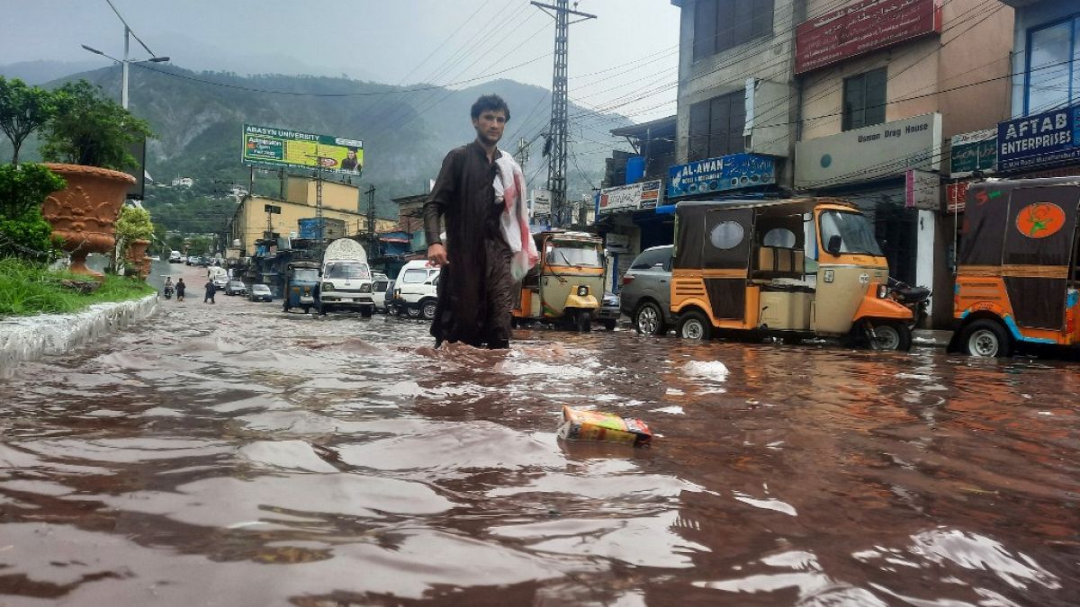 Um homem atravessa uma rua inundada em Muzaffarabad, Paquistão
